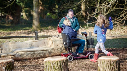 Grandparents and a grandchild play together in the Log Stack play area in Dyffryn Gardens during the winter